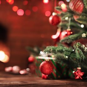 Christmas Tree with Decorations Near a Fireplace with Lights
